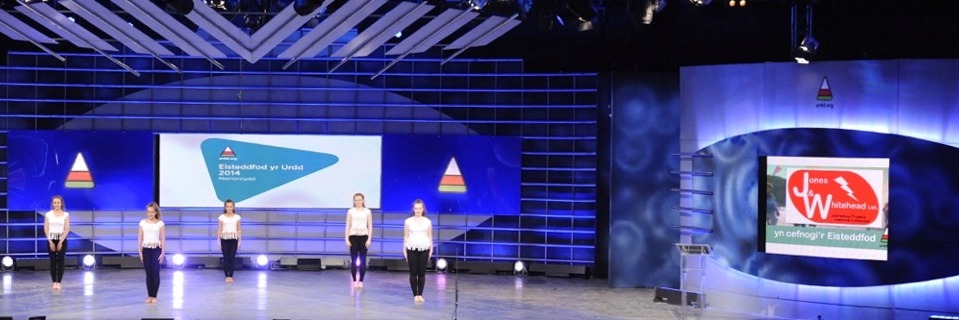 Urdd Eisteddfod pavilion stage with the Jones & Whitehead logo on screen